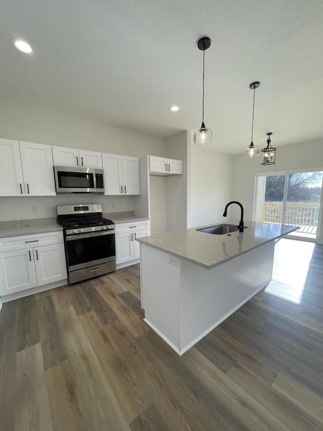 kitchen featuring sink, decorative light fixtures, a center island with sink, appliances with stainless steel finishes, and white cabinets