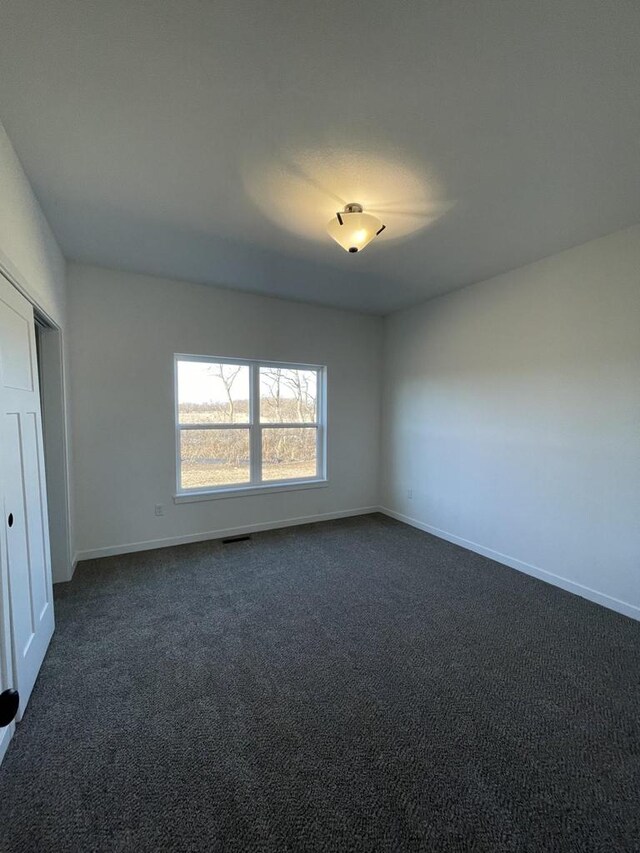 3272 S Bartells Dr, Beloit, WI 53511 - unfurnished bedroom featuring baseboards and dark colored carpet