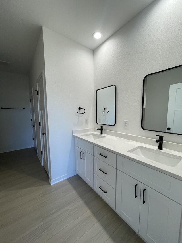 3272 S Bartells Dr, Beloit, WI 53511 - full bath with baseboards, double vanity, a sink, and wood finished floors