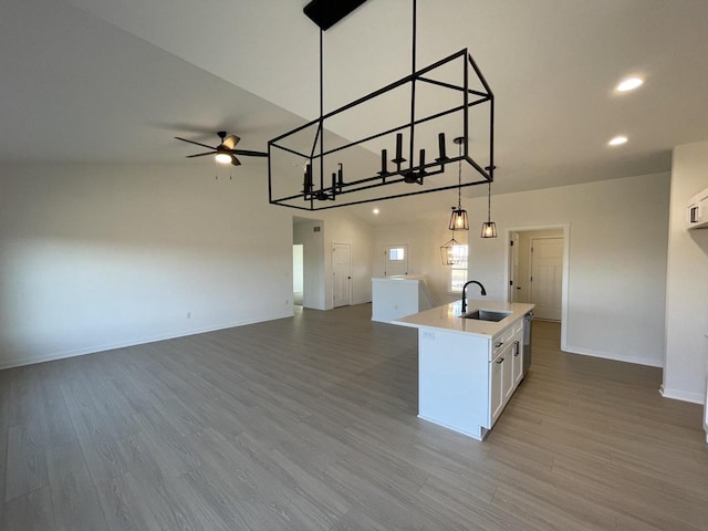 kitchen with a sink, open floor plan, light wood-style floors, and an island with sink