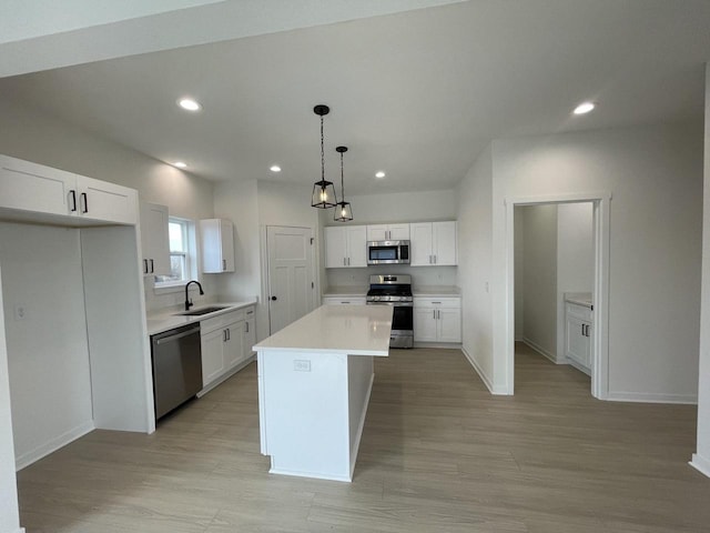 kitchen featuring pendant lighting, sink, white cabinetry, stainless steel appliances, and a kitchen island