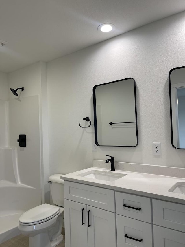 bathroom featuring walk in shower, vanity, and toilet