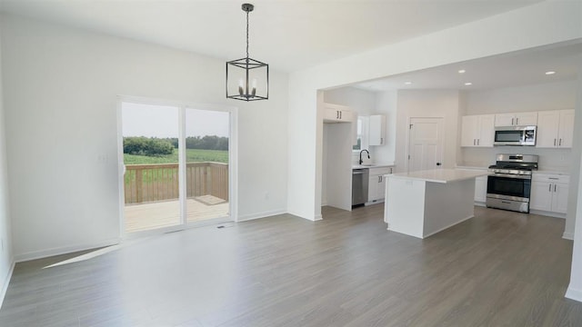 kitchen with white cabinetry, wood-type flooring, a center island, pendant lighting, and stainless steel appliances