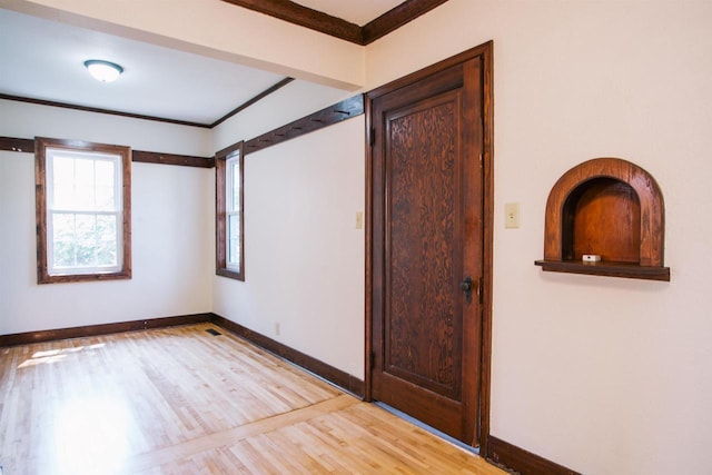 empty room featuring ornamental molding and light wood-type flooring