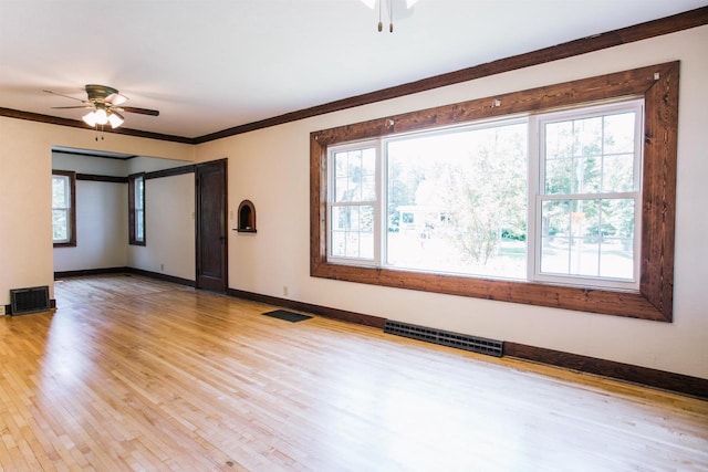 spare room featuring ceiling fan, a healthy amount of sunlight, ornamental molding, and light hardwood / wood-style floors