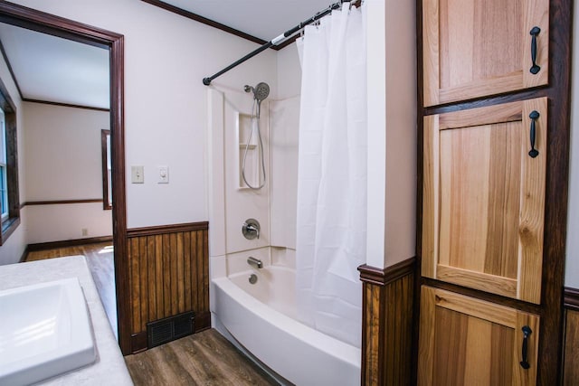 bathroom featuring wooden walls, hardwood / wood-style flooring, ornamental molding, vanity, and shower / bath combo