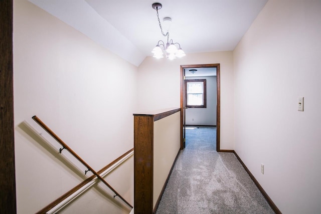 corridor with lofted ceiling, light colored carpet, and an inviting chandelier