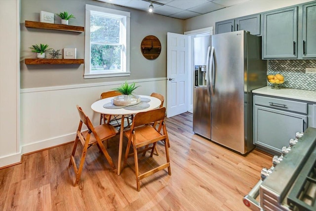 kitchen with light wood-type flooring, backsplash, and stainless steel fridge with ice dispenser