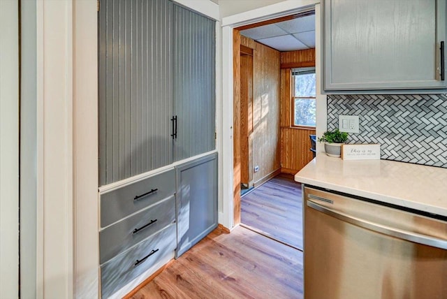 kitchen with gray cabinetry, light hardwood / wood-style floors, tasteful backsplash, and stainless steel dishwasher