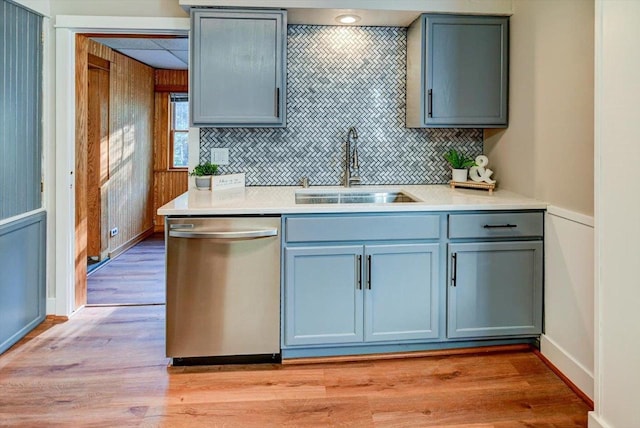 kitchen featuring stainless steel dishwasher, sink, light hardwood / wood-style flooring, and tasteful backsplash