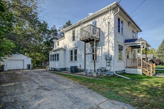 view of front of house featuring a balcony, cooling unit, an outdoor structure, a garage, and a front yard