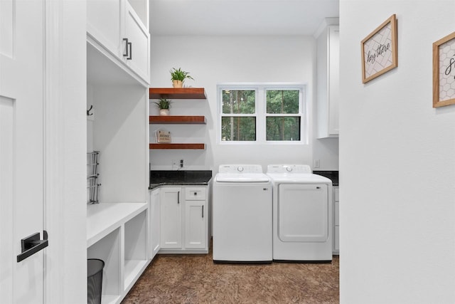 clothes washing area featuring cabinets and separate washer and dryer