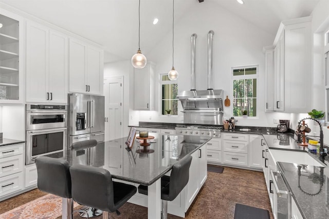 kitchen with sink, hanging light fixtures, dark stone counters, stainless steel appliances, and white cabinets