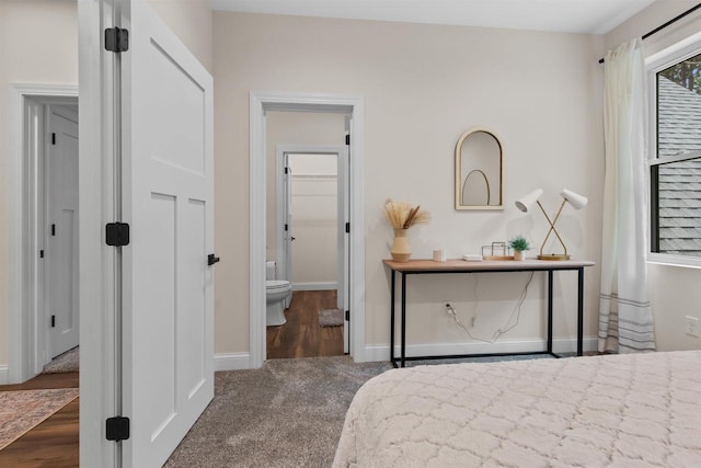 bedroom featuring connected bathroom and dark colored carpet