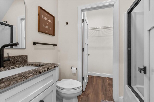 full bathroom with vanity, hardwood / wood-style floors, combined bath / shower with glass door, and toilet