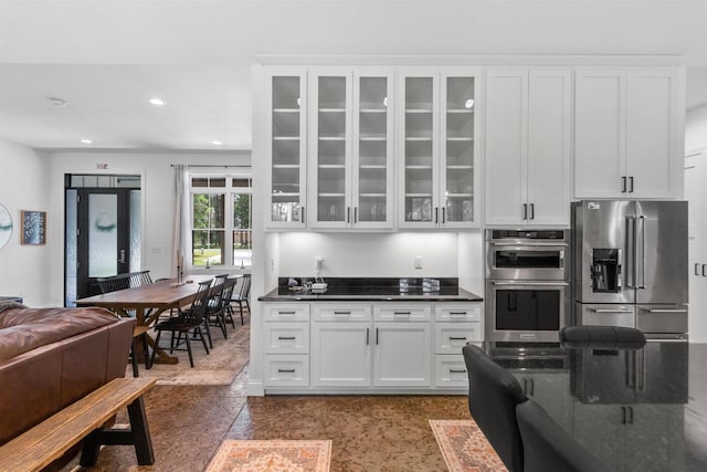 kitchen featuring white cabinetry, appliances with stainless steel finishes, and dark stone countertops