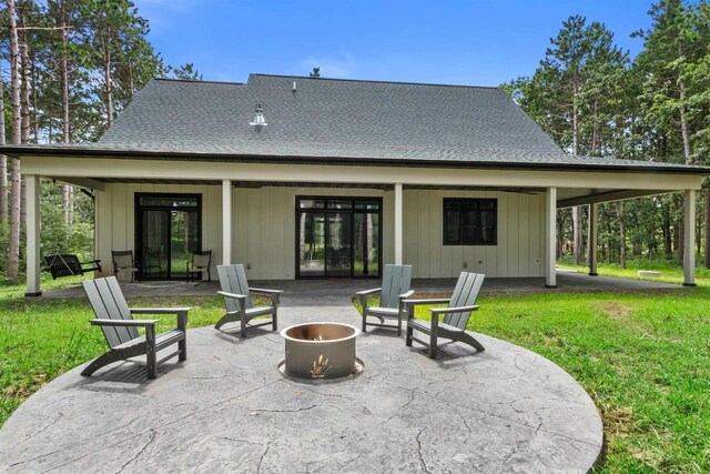 back of property with a yard, a patio area, and a fire pit