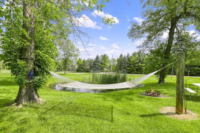 view of community with a yard and an outdoor fire pit
