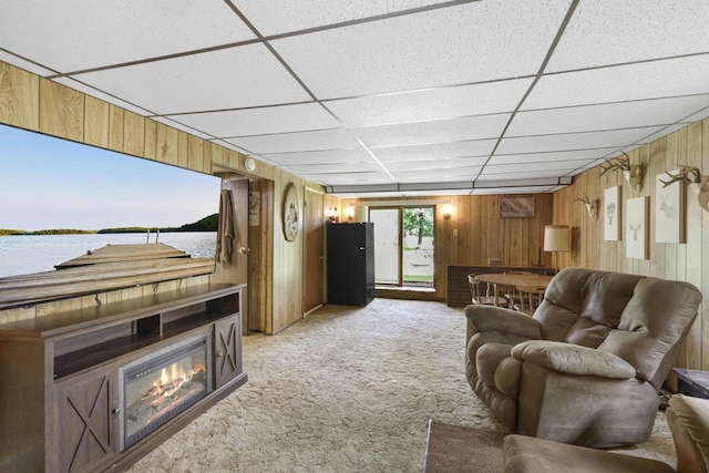 carpeted living room with wood walls and a drop ceiling