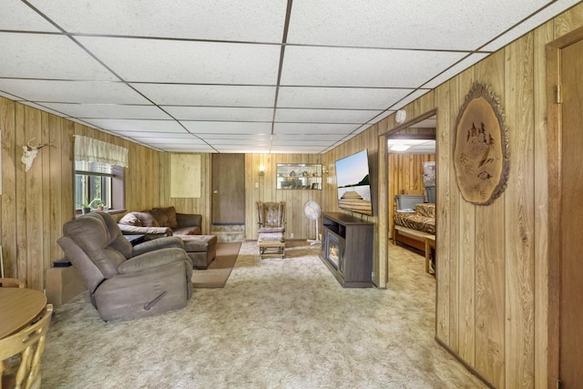 carpeted living room with a drop ceiling and wooden walls