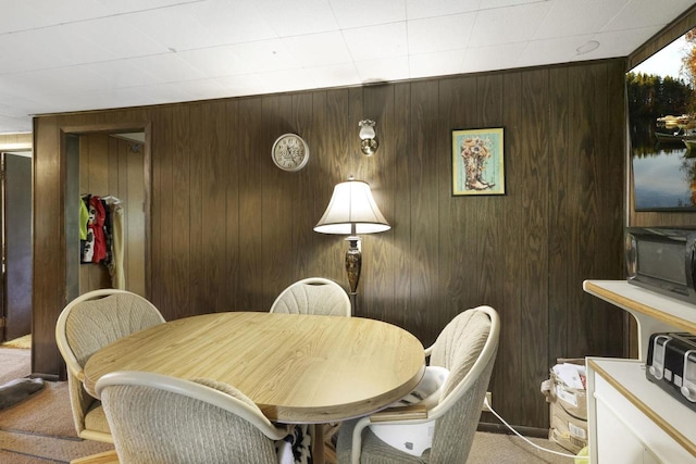 dining room with light colored carpet and wooden walls
