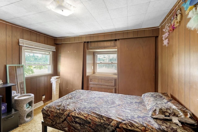 carpeted bedroom featuring wooden walls