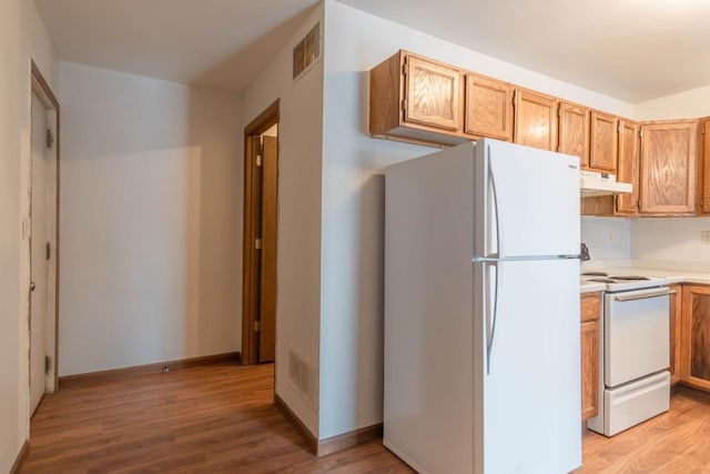 kitchen with white appliances and light hardwood / wood-style floors