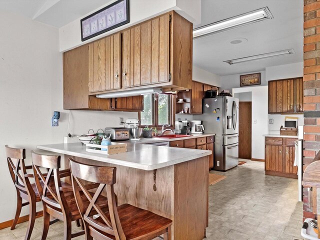 W7031 Hickory Ln, Elkhart Lake, WI 53020 - kitchen with light countertops, brown cabinetry, a peninsula, and a breakfast bar area