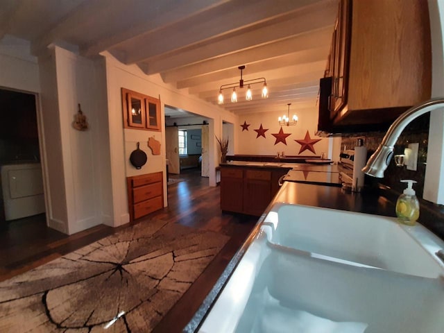 kitchen with beamed ceiling, dark wood-type flooring, a barn door, decorative light fixtures, and washer / clothes dryer