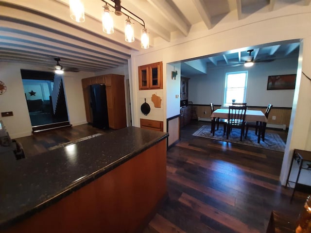 kitchen featuring ceiling fan, pendant lighting, beam ceiling, dark hardwood / wood-style flooring, and dark stone countertops