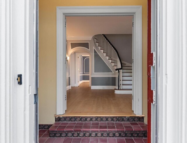 staircase featuring crown molding and wood-type flooring