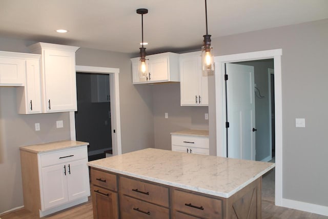 kitchen featuring white cabinetry, decorative light fixtures, light stone countertops, and a kitchen island