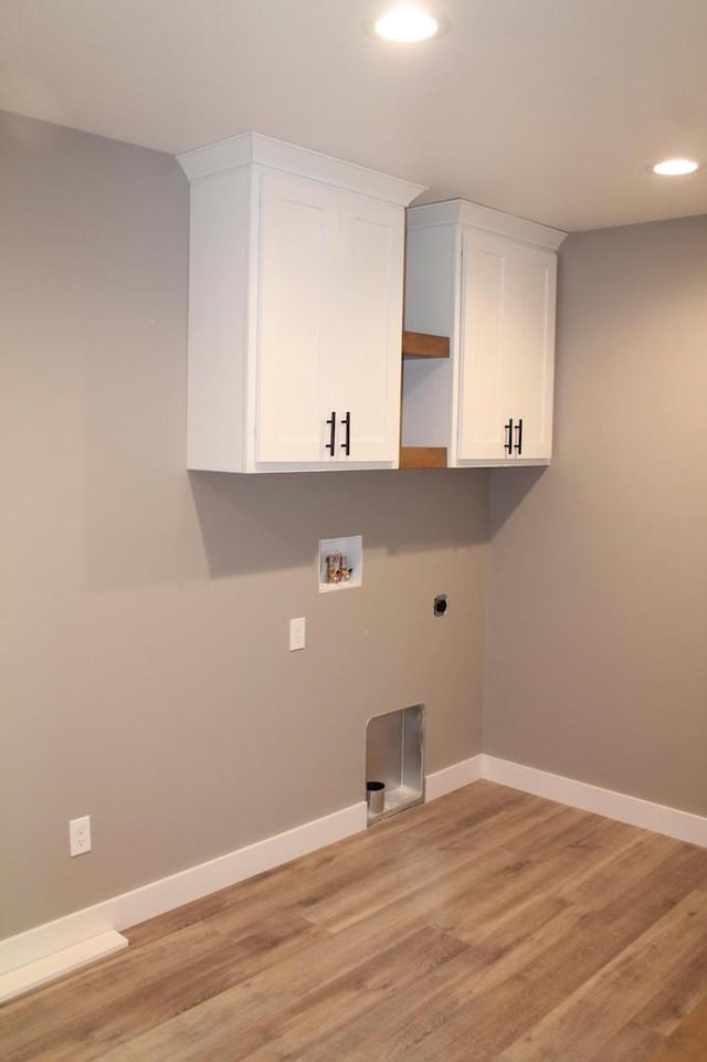 laundry room with washer hookup, electric dryer hookup, light hardwood / wood-style floors, and cabinets