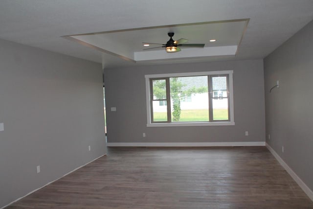 spare room featuring dark hardwood / wood-style flooring, a raised ceiling, and ceiling fan