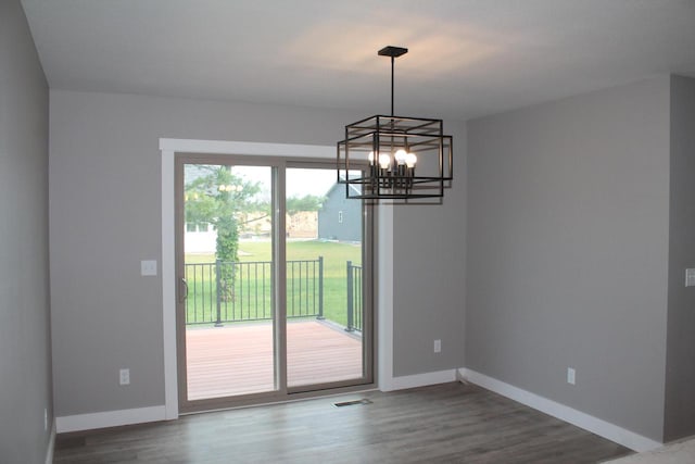 unfurnished dining area with an inviting chandelier and hardwood / wood-style floors