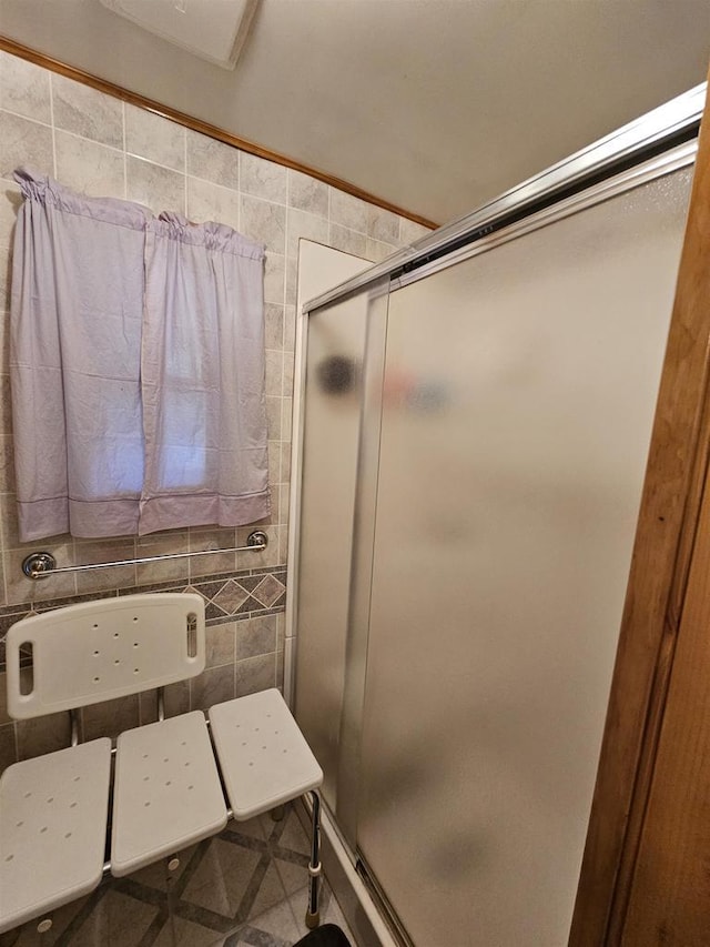 bathroom with tile walls and a shower with shower door