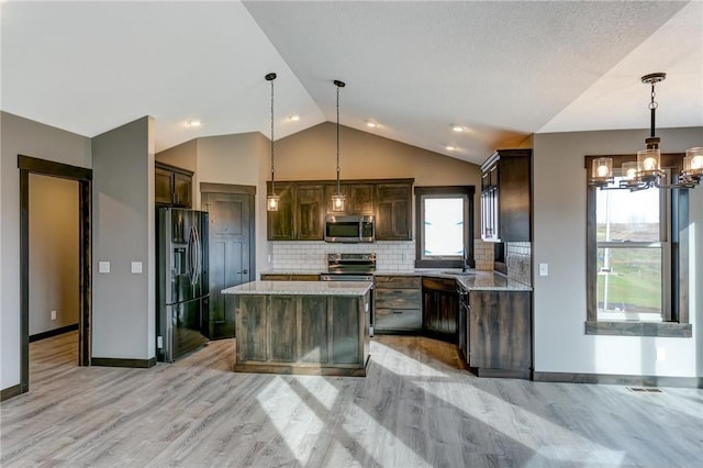 kitchen with hanging light fixtures, appliances with stainless steel finishes, a center island, and dark brown cabinetry