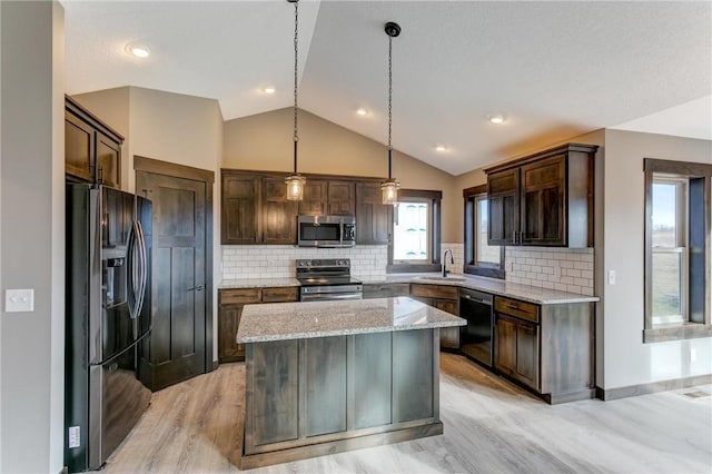 kitchen with sink, a center island, black appliances, light stone countertops, and decorative light fixtures