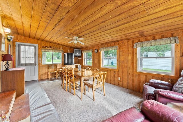 dining room with wooden walls, lofted ceiling, light colored carpet, ceiling fan, and wood ceiling