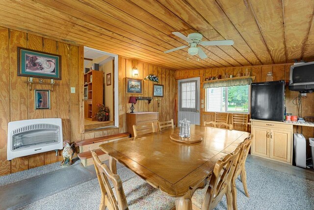 carpeted dining area with heating unit, wood ceiling, and wood walls