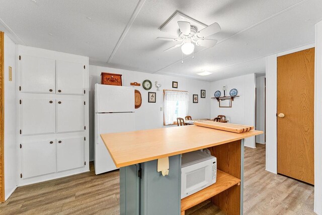 kitchen with ceiling fan, light wood-type flooring, a textured ceiling, and white appliances