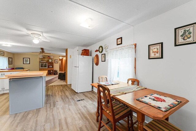 dining space with ceiling fan, a textured ceiling, and light wood-type flooring