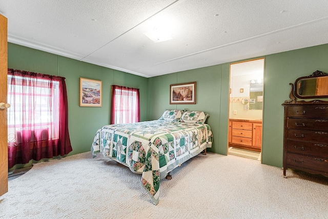 carpeted bedroom with ensuite bathroom, multiple windows, and a textured ceiling