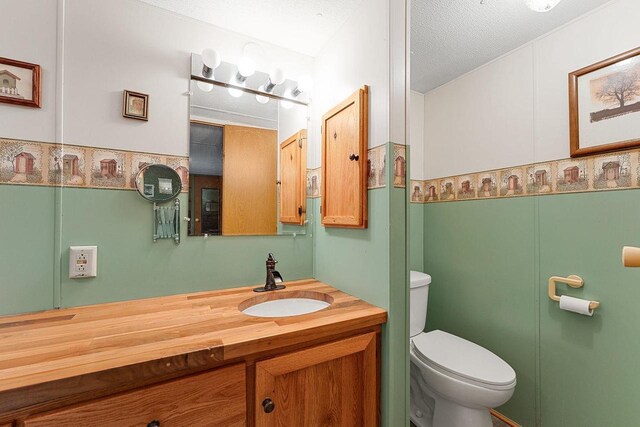 bathroom featuring vanity, toilet, and a textured ceiling