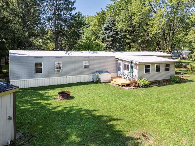 rear view of house with a yard, a fire pit, and a deck