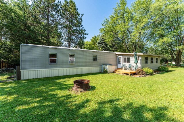 rear view of property with a yard, a deck, and an outdoor fire pit