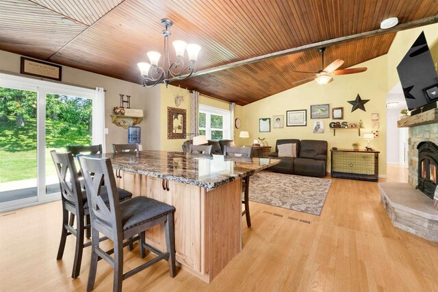 W12203 State Road 23, Ripon, WI 54971 - kitchen featuring a fireplace, ceiling fan with notable chandelier, a kitchen bar, light hardwood / wood-style floors, and wood ceiling