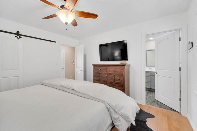 W12203 State Road 23, Ripon, WI 54971 - bedroom featuring light hardwood / wood-style floors, ensuite bathroom, a barn door, and ceiling fan