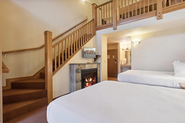 bedroom featuring a tile fireplace and a high ceiling