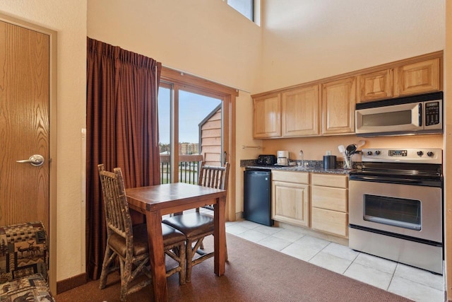 kitchen featuring a towering ceiling, stainless steel appliances, and light tile patterned flooring